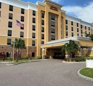A hotel with a parking lot and trees in front of it.