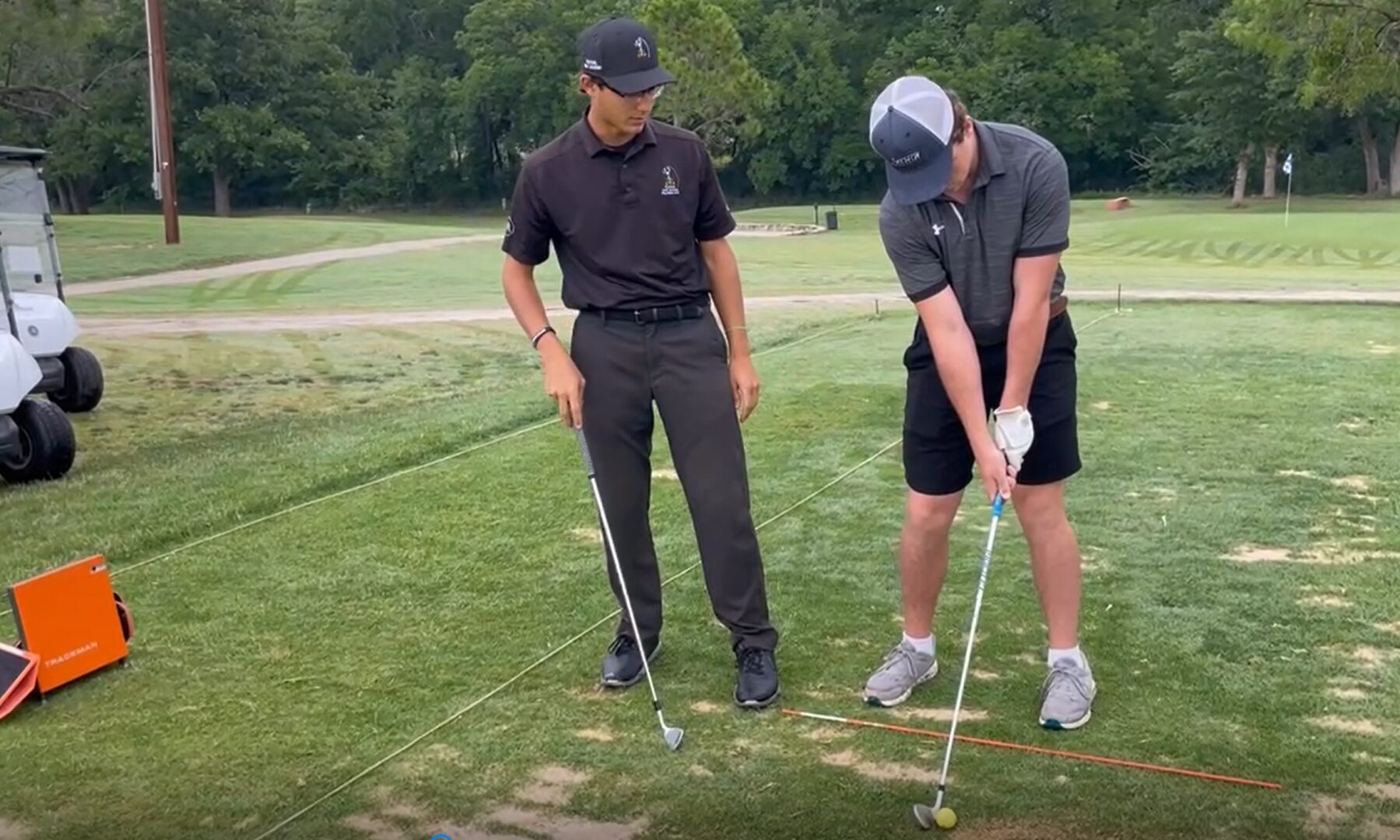lesson Two men are playing golf on a green.