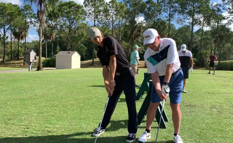 Two men are playing golf on a green.