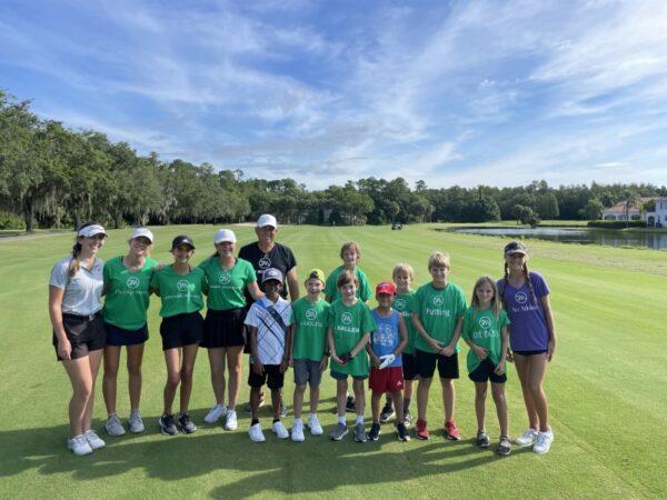 A group of people standing on top of a golf course.