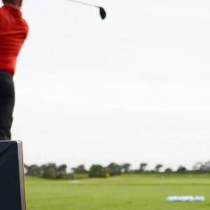 A man swinging at the golf ball on a course.