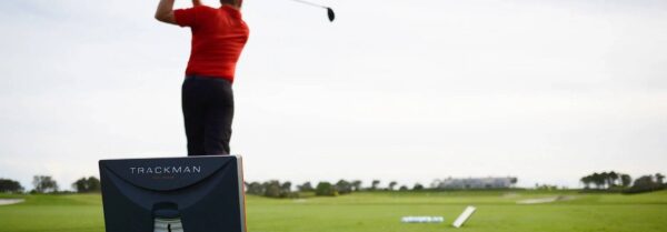 A man swinging at the golf ball on a course.