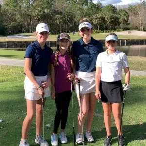 Four women are posing for a picture on the golf course.