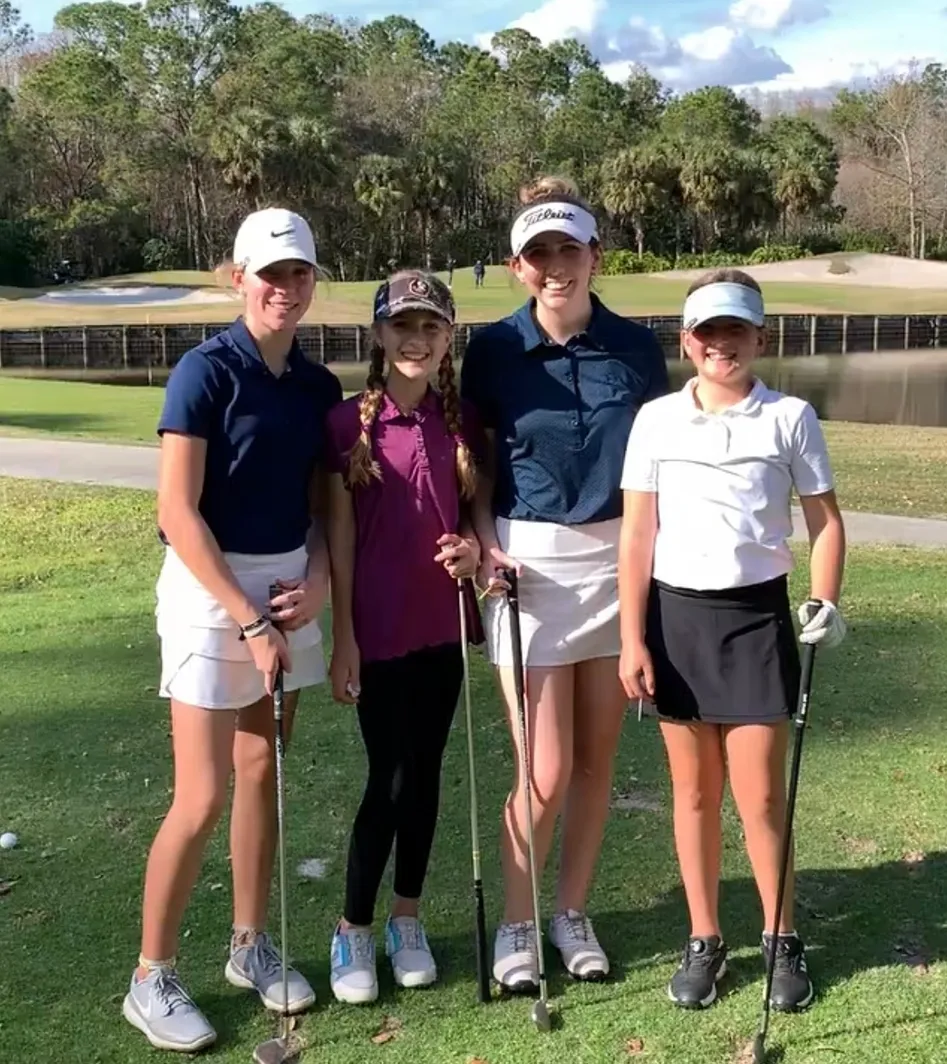 Four girls posing for a photo holding a golf bat