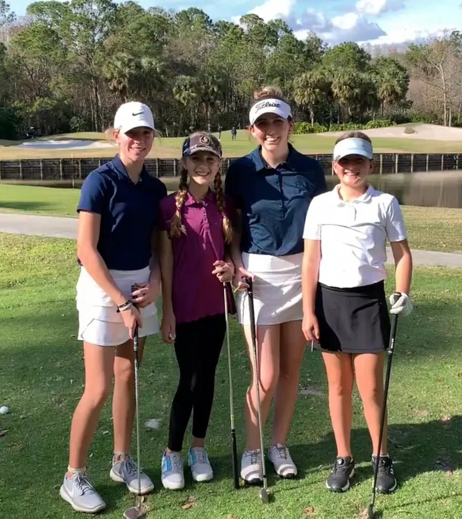 Four women are posing for a picture on the golf course.