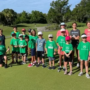 A picture of kids and adults taken on a golf course