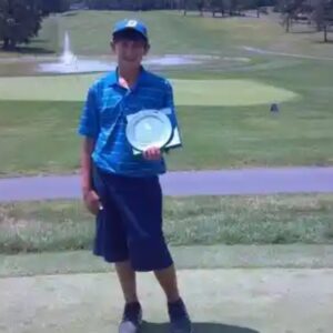 A man holding a frisbee on top of a golf course.